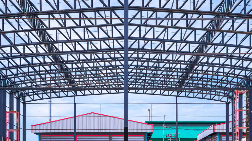 Metal roof beam and columns of incomplete warehouse building structure in construction site